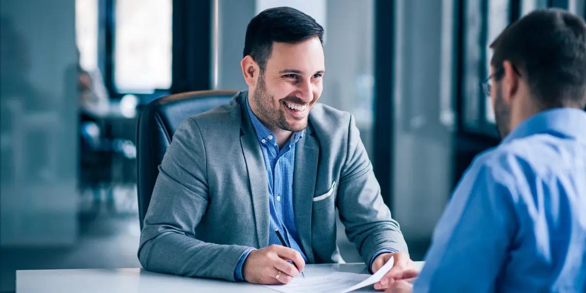 Corretor de imóveis utilizando técnicas de vendas para imobiliárias para fechar negócio com cliente.