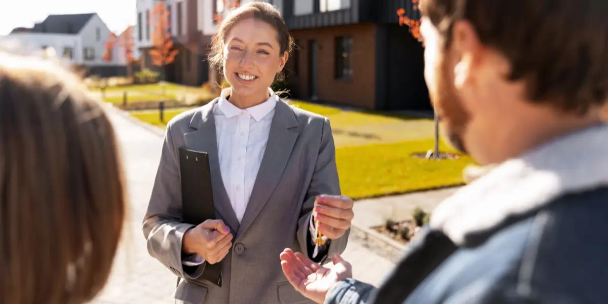 Corretora de imóveis entregando chaves de um imóvel alugado para seus clientes.