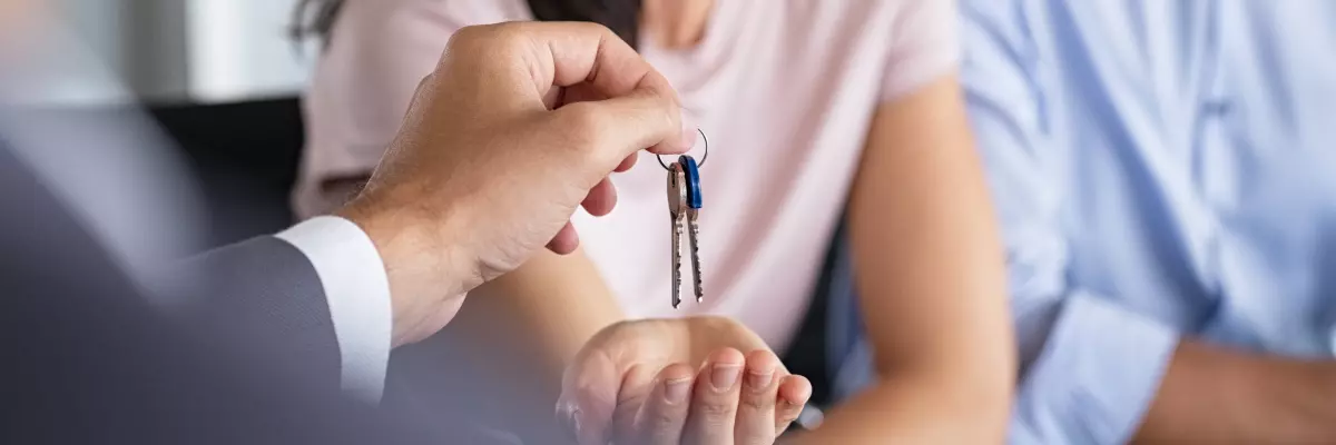 Imagem ilustrativa de um corretor de imóveis entregando as chaves para um cliente.