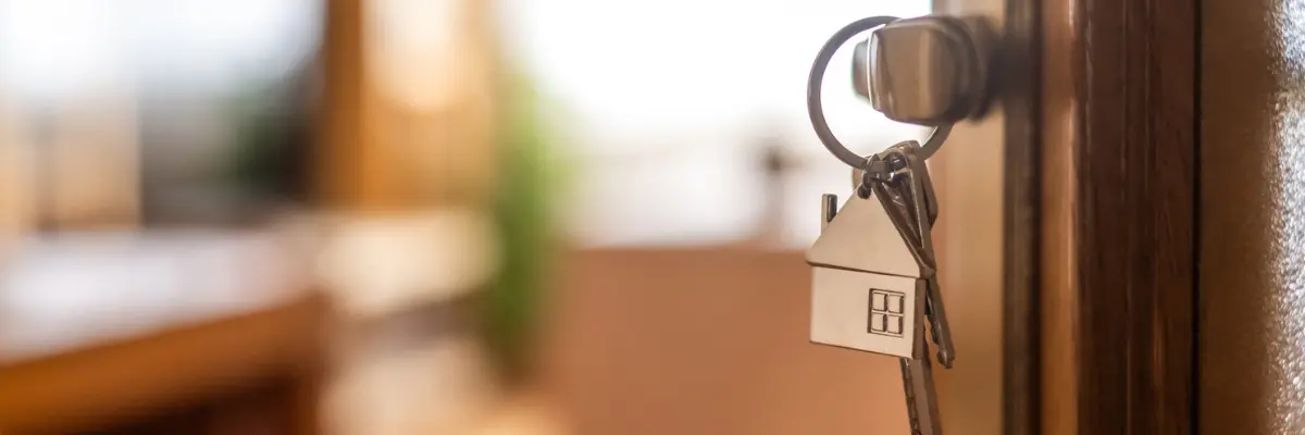 Imagem de uma chave na porta de uma casa nova.
