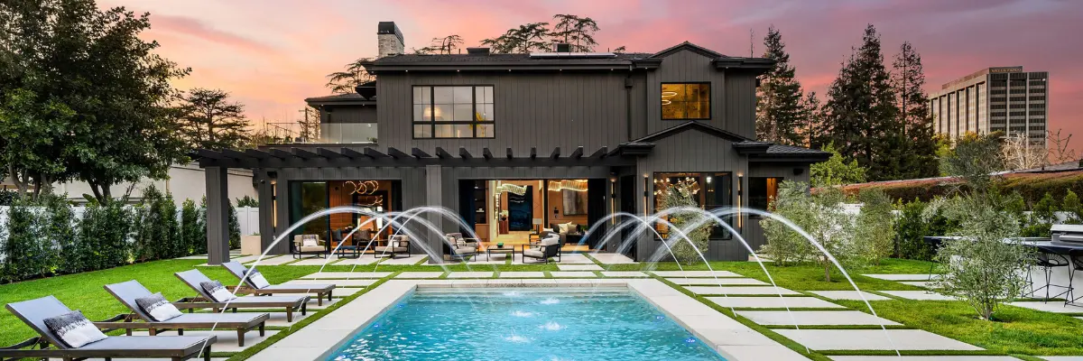 Área da piscina de um imóvel de luxo ao entardecer.