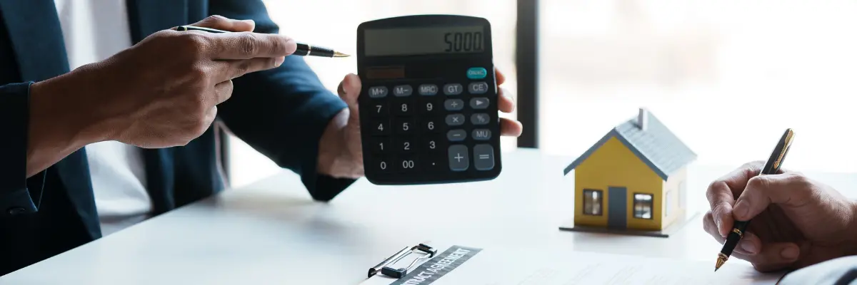 Corretor imobiliário calculando valor da transferência de imóvel para cliente.