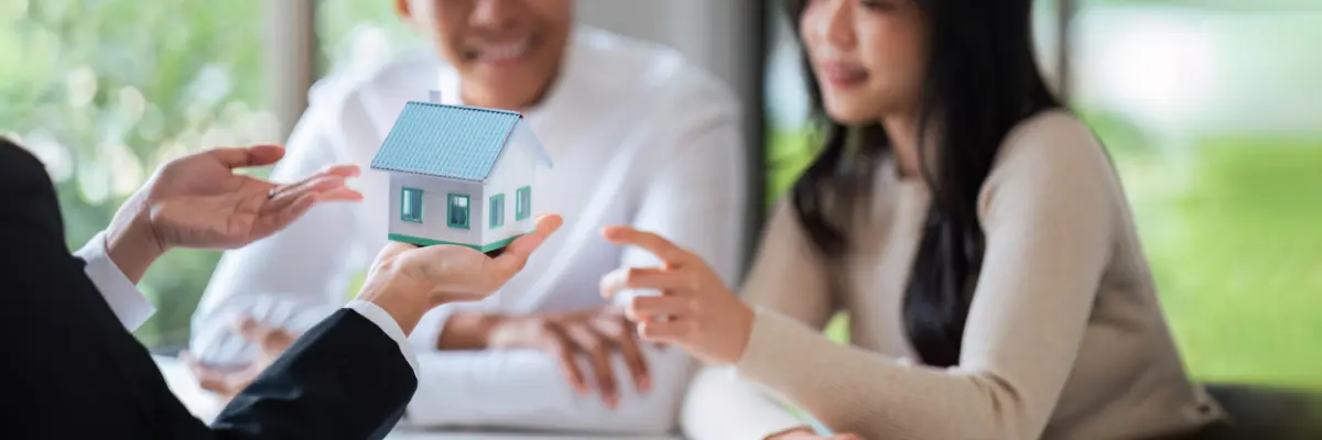 Casal conversando com corretor de imóveis sobre juros do financiamento imobiliário na compra de apartamento.