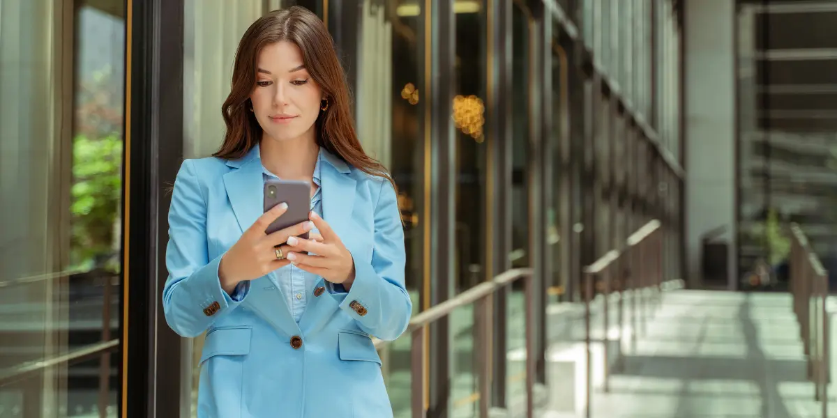 Corretora de imóveis usando aplicativos para gestão imobiliária em seu celular.