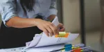 Imagem de uma corretora analisando documentos para a venda de imóveis.