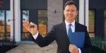Corretor de imóveis segurando chave de casa para entregar para cliente.